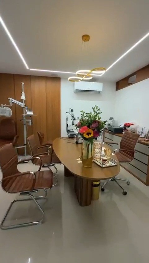 Sala do consultório com mesa comprida e arranjo de flores
