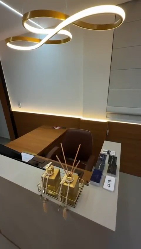 Recepção do consultório com balcão e luminária dourada