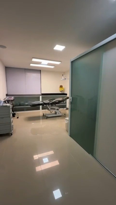 Sala de procedimentos ampla, separada por porta de vidro